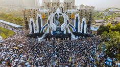 an aerial view of a large crowd gathered in front of a building with a giant screen