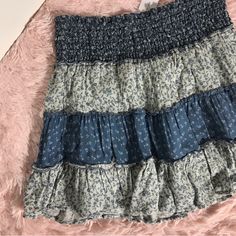 a skirt with blue and white ruffles on it sitting on a pink blanket