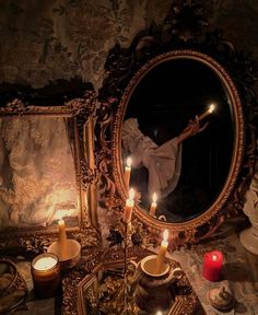 a mirror with candles in front of it and a person holding a lit candle behind it