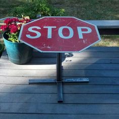 a red stop sign sitting on top of a wooden deck next to potted plants