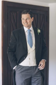 a man wearing a suit and tie standing in front of a door