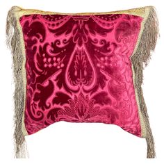 a pink and gold pillow with fringes on the bottom, in front of a white background