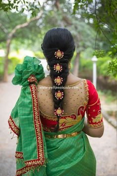 a woman in green and red sari walking down the street with her back to the camera