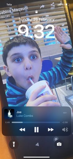 a cell phone with an image of a boy drinking from a cup