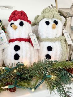 two snowmen sitting on top of a mantle next to pine cones and christmas decorations