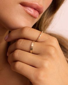 a woman wearing a gold wedding band with a diamond ring on her finger, close up