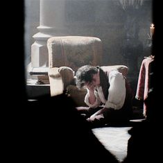 a woman is sitting on the floor in front of a chair with her head down