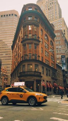 a yellow taxi cab driving down a street next to tall buildings