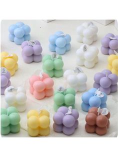 many different colors of balloons are arranged on a white surface with one balloon in the middle