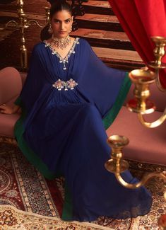 Make a statement at your next Sangeet or cocktail party in this stunning Electric Blue Chiffon Kaftan. With its exquisite embroidery along the neckline and sleeves, this Indo-Western draped kaftan offers the perfect blend of comfort and style for wedding guests. The flowing chiffon fabric drapes beautifully, creating a luxurious silhouette that's ideal for festive occasions. Whether it's a Sangeet or a cocktail event, this kaftan ensures you exude elegance. Composition : Kaftan - Chiffon & Lining - Satin Care: Dry Clean Only and Vacuum Storage This product can be customized for sleeves, blouse length and neckline Delivery : 2-4 weeks as the product is hand crafted. Check Size Guide or choose MySize for free customisation (All Sizes above XL can be made at 15% additional cost) For more info Designer Embroidered Neckline Dress For Diwali, Festive Silk Kaftan With Cape Sleeves, Diwali Georgette Kaftan With Dupatta, Evening Kaftan With Dupatta, Silk Kaftan With Zari Work For Reception, Silk Floor-length Kaftan With Dabka Work, Elegant Kurta With Zari Work And Cape Sleeves, Traditional Georgette Kaftan With Dupatta, Floor-length Georgette Kaftan With Dupatta