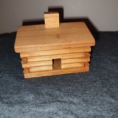 a small wooden toy house sitting on top of a blue bed cover covered in gray carpet