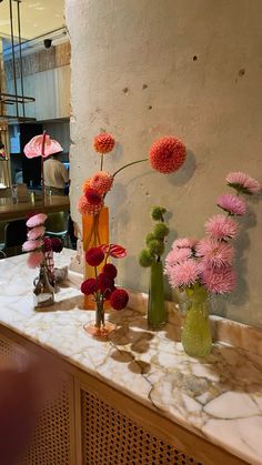 several vases with flowers on a marble counter