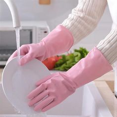 a person wearing pink gloves is washing vegetables in a kitchen sink with a white heart shaped dishwasher