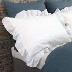 a bed that has some pillows on top of it and is next to a brick wall