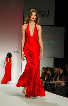 a woman in a red dress walking down the runway