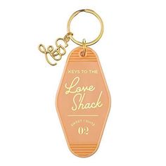 a keychain with the words love shack written in gold on it and an orange bottle