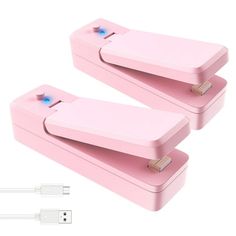 two pink nintendo wii controllers sitting side by side on top of each other, with one being plugged in