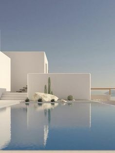 an empty swimming pool next to a white building with cactus growing on it's side