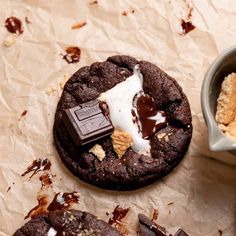 two chocolate cookies with marshmallows and ice cream on top, next to a cup of coffee