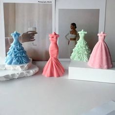 three different colored dresses are on display in front of a mirror with a woman taking a photo