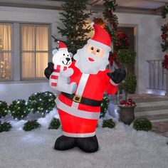 an inflatable santa claus holding a polar bear on the front lawn of a house