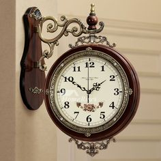 a clock hanging from the side of a wall next to a doorway with an ornate frame