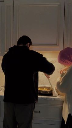 a man and woman preparing food in a kitchen