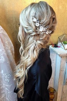 a woman with long blonde hair and flowers in her hair is standing near a dresser