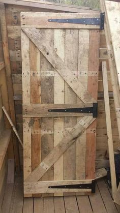 an open wooden door sitting on top of a pile of pallet wood planks