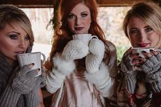 three beautiful women holding coffee mugs in their hands while wearing knitted mittens