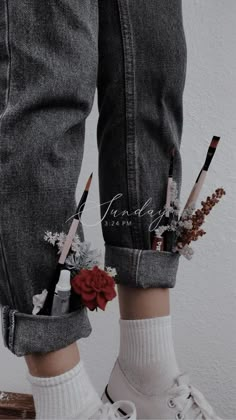 a pair of legs with flowers and pencils sticking out of the pocket on them