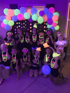 a group of girls wearing neon glasses and holding up their party hats in front of a purple background