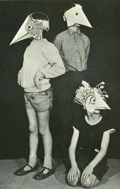 two children with masks on their heads and one child wearing a bird mask while the other is sitting down