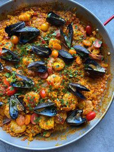 a pan filled with seafood and rice on top of a table