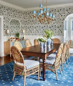 a dining room with blue and white wallpaper, wicker chairs and a wooden table