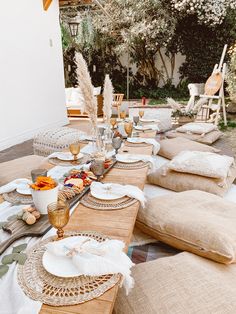 a table set up with place settings and plates on it for an outdoor dinner party