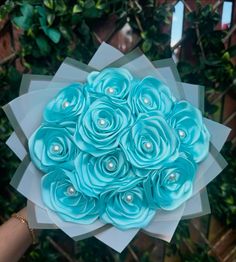 a person holding a bouquet of blue flowers in their hand with pearls on the petals