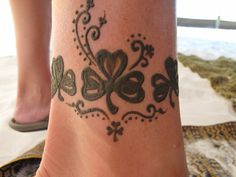 a close up of a person's foot with tattoos on it and shamrocks