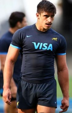 a man standing on top of a soccer field wearing a black and blue shirt with the word visa written on it