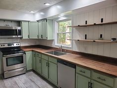 an empty kitchen with green cabinets and stainless steel appliances