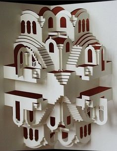 a sculpture made out of white paper with red and white buildings on it's sides