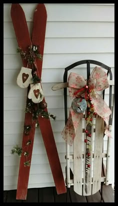 two wooden sleds are decorated with bows and ornaments on the side of a house