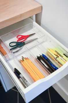 an organized drawer with pens, scissors and pencils in it on the counter top