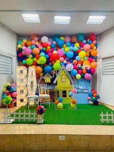 an indoor play area with colorful balloons on the wall and fake grass in front of it