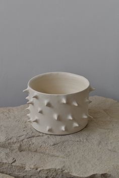 a white ceramic bowl sitting on top of a stone slab in front of a gray wall