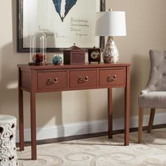 a table with two drawers and a lamp on it in front of a framed poster