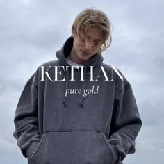 a young man wearing a grey sweatshirt with the words ketchan pure gold on it