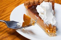 a piece of pie on a white plate with a fork in it and whipped cream on top