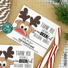 two christmas cards on top of a brown paper bag with candy canes and pine cones