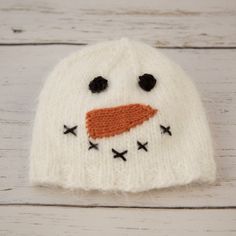 a knitted snowman hat sitting on top of a wooden table